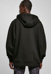 Schwarzer oversized Hoodie mit einer Kordelzugkapuze, gerippten Bündchen und Saum. Hergestellt aus weichem Material, zeichnet sich durch eine lockere Passform und eine glatte Textur aus.