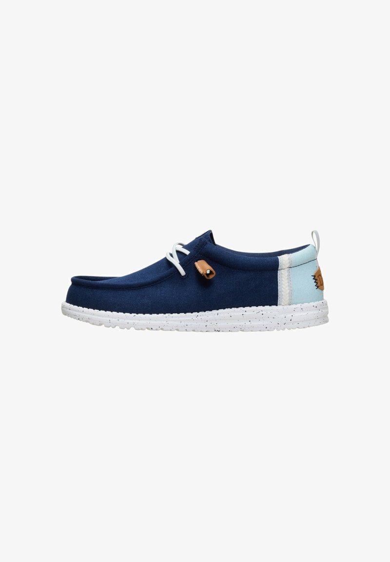 Chaussure bateau bleu marine avec talon bleu clair, semelle blanche mouchetée, lacets blancs et accent en cuir marron clair sur le côté et la languette arrière.