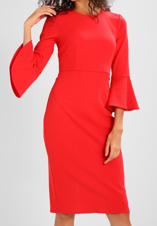 Femme portant une robe rouge vif cintrée à la longueur du genou avec des manches évasées trois-quarts, debout devant un fond gris clair.