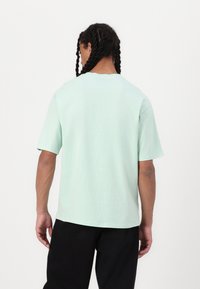 Mint green cotton t-shirt with short sleeves and a crew neck, featuring a relaxed fit and smooth texture. No visible patterns or accents.