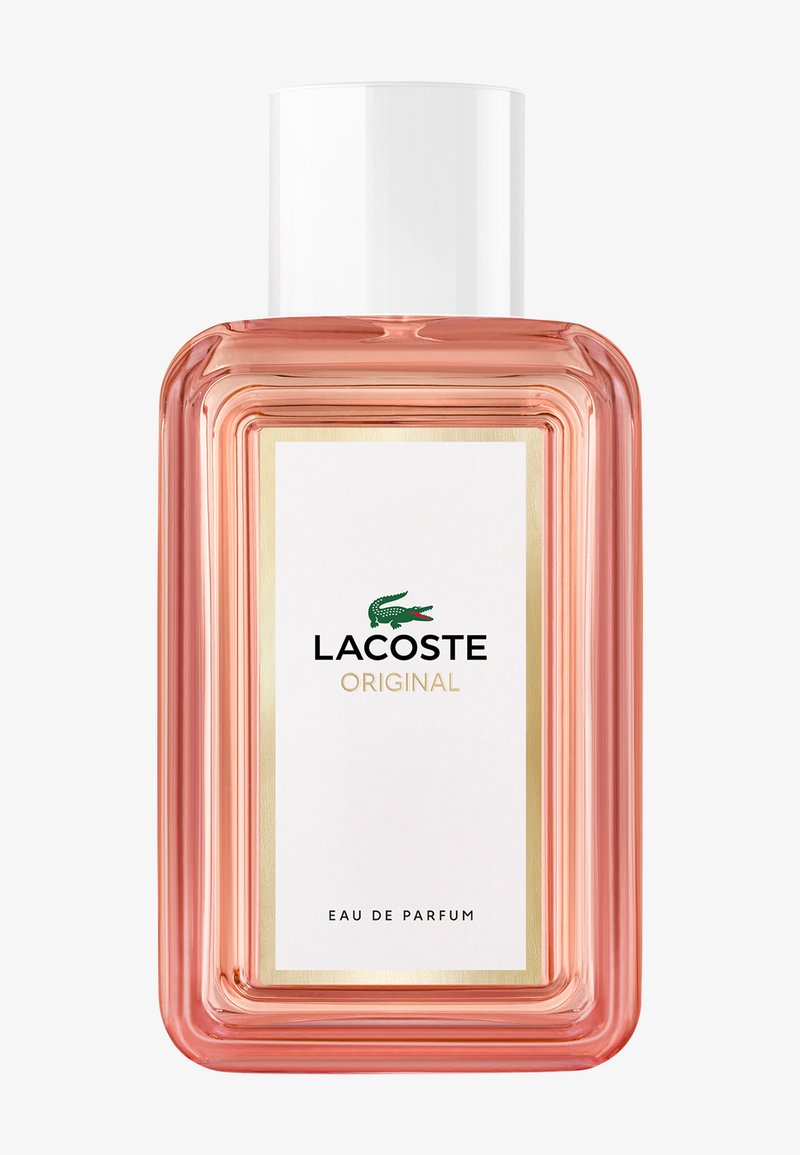 Lacoste Original eau de parfum i en rektangulær glassflaske med rosa skjær, hvit kork, hvit etikett og grønn krokodillelogo.