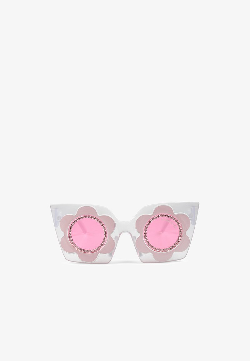 Des lunettes de soleil œil de chat avec des montures transparentes, des accents en forme de fleurs roses entourant des verres ronds roses, ornées de strass.