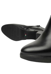 Stivali ankle in pelle nera con finitura liscia, zip laterale e suola in gomma con motivo, dotati di tacco e dettaglio della bandiera italiana.