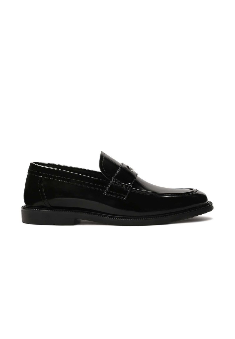 Black patent leather loafers with a rounded toe, decorative strap, and textured stitching on the upper. Smooth, shiny finish. Flat sole.
