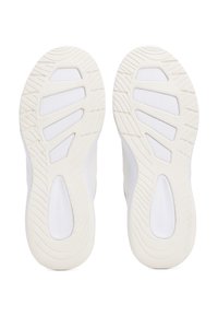 Paire de semelles de baskets blanches avec des motifs de bande de roulement géométriques et des sections de préhension texturées, vues par le dessous.