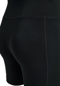 Czarne szorty sportowe wykonane z elastycznej tkaniny, charakteryzujące się gładką powierzchnią, średnim stanem i płaskimi szwami dla komfortu.