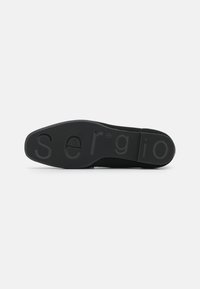 Zapatilla negra con parte superior de malla texturizada, suela de goma con marca elevada y un diseño aerodinámico para una apariencia moderna.