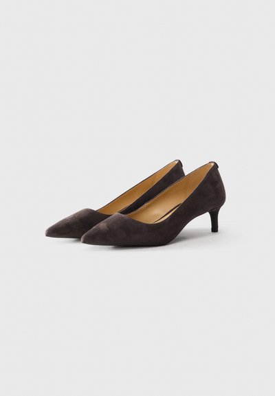 Une paire de chaussures pour femmes en daim marron foncé, à bout pointu et à petit talon, sur un fond gris clair, inclinées vers la droite.