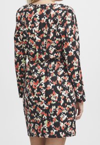Robe à manches longues ornée d'un imprimé abstrait coloré en rouge, vert et crème sur fond noir, avec une taille ceinturée et une courte longueur.