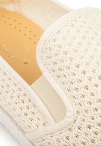 Beige geweven instapper met een ademende mesh bovenkant, gladde afwerking en een gevoerde binnenkant met perforaties voor luchtcirculatie.