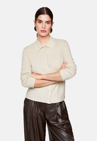 Cremefarbener, gerippter Strickcardigan mit Kragen, Knopfleiste, Dreiviertelärmeln und lässiger Passform.