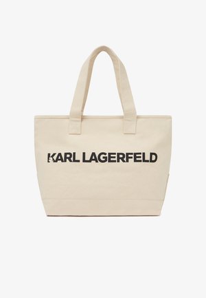 Beżowa torba na ramię z płótna z dwoma uchwytami i napisem "KARL LAGERFELD" wytłoczonym grubymi czarnymi literami na przedniej stronie.