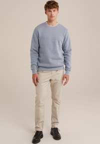 Sweatshirt de culoare albastru deschis cu guler rotund, manșete și tiv cu nervuri, asortat cu pantaloni chino bej și pantofi negri cu șireturi. Textură netedă.
