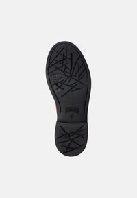 Suela de goma negra con un patrón texturizado de líneas entrelazadas, que presenta un destacado logotipo de "Camper" y la marca de tamaño.