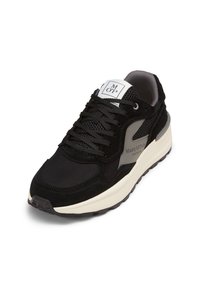 Černé tenisky vyrobené z materiálů síťoviny a semiše, kulatá špička, silná bílá mezipodešev a šedé akcenty. Logo na jazyku.