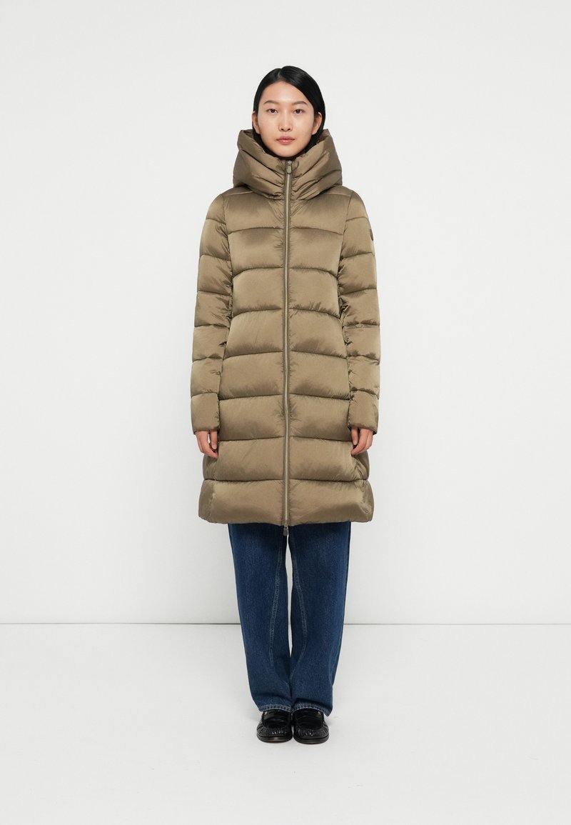 Cappotto lungo imbottito di colore verde oliva con colletto alto e chiusura con zip. Presenta una linea dritta ed è caratterizzato da un trapuntato orizzontale.