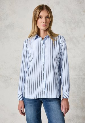 Light blue button-up shirt with dark vertical stripes, long sleeves, and a collar, made from a smooth fabric. Worn with blue jeans.