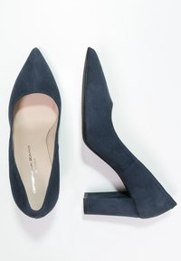Mörkblå mockaskor med hög klack och spetsig tå, med en kraftig klack och en mjuk inredning.