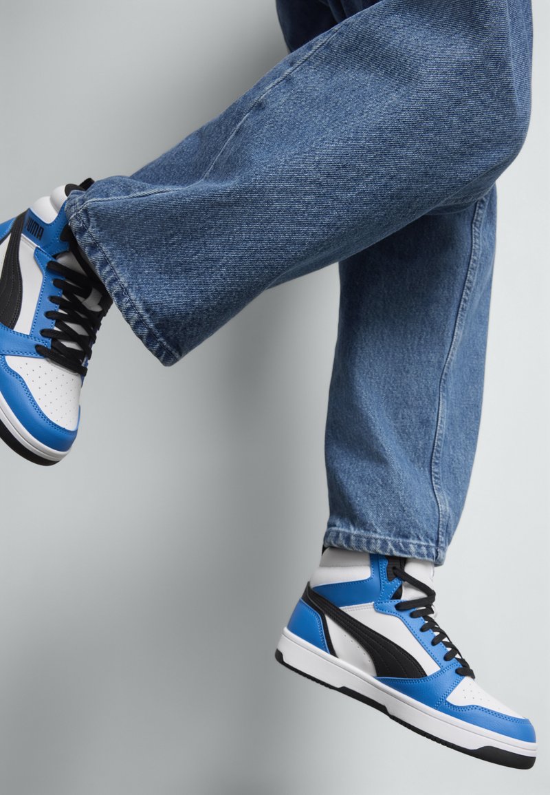 Blauwe en witte hoge sneakers met zwarte accenten. Glad leren en textielmateriaal. Geperforeerd teengedeelte en contrasterende zool.