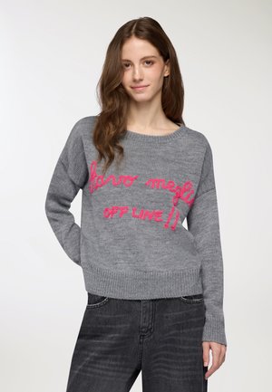 Maglione grigio lavorato a maglia con scollo rotondo e maniche lunghe. Il testo rosa "staro megly OFF LINE!!" è in evidenza sul davanti.
