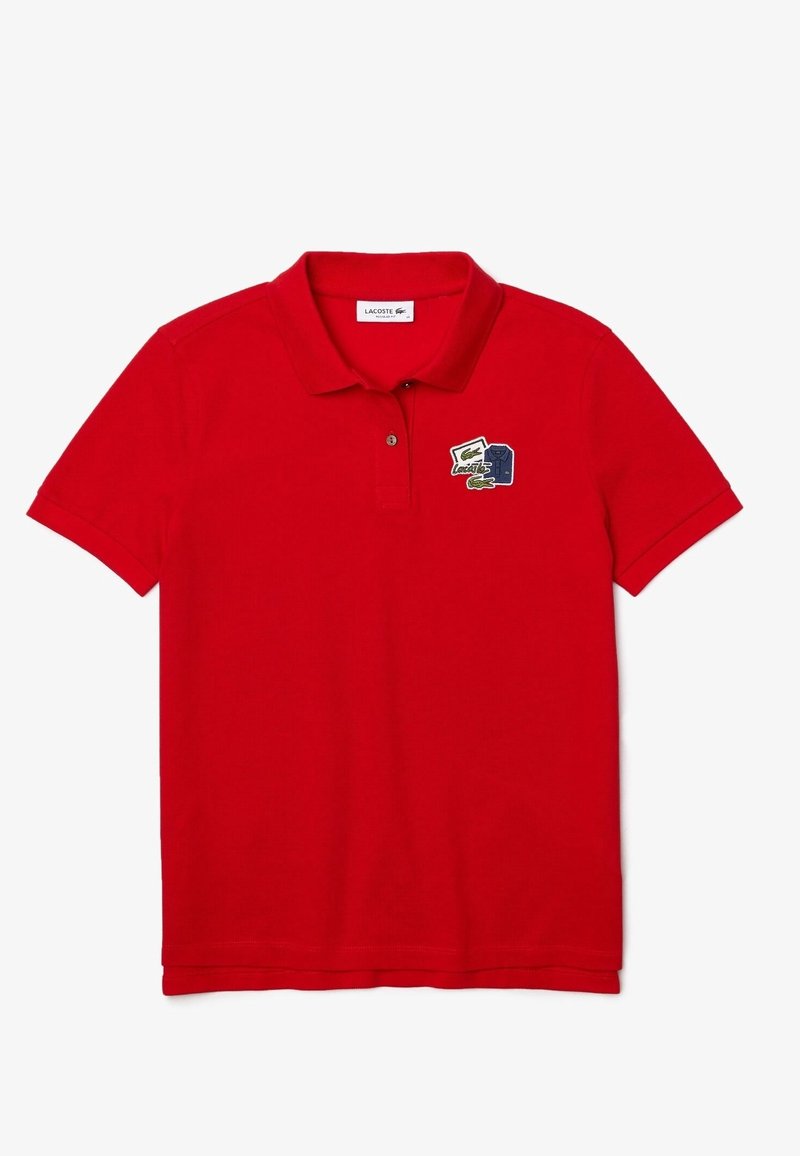 Červená bavlněná polo tričko s límečkem, tříknoflíkovým zapínáním a vyšitým logem Lacoste na levé hrudi. Hladká textura.
