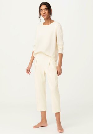 Top leggero a maniche lunghe di colore crema abbinato a pantaloni cropped su misura. Tessuto morbido con una sottile trama. Design semplice e rilassato.