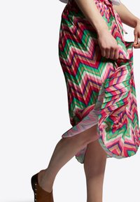 Jupe colorée à motif zigzag avec des nuances de rose, vert et marron. Tissu léger, longueur genoux avec une taille élastique et un cordon de serrage.