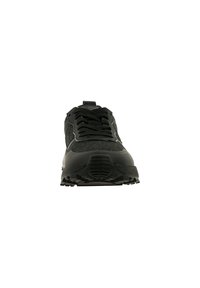 Chaussure de sport noire avec semelle texturée et lacets à l'avant, visible depuis un angle frontal centré sur fond blanc.