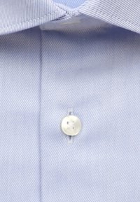Light blue dress shirt collar and top button with fine diagonal weave texture visible.