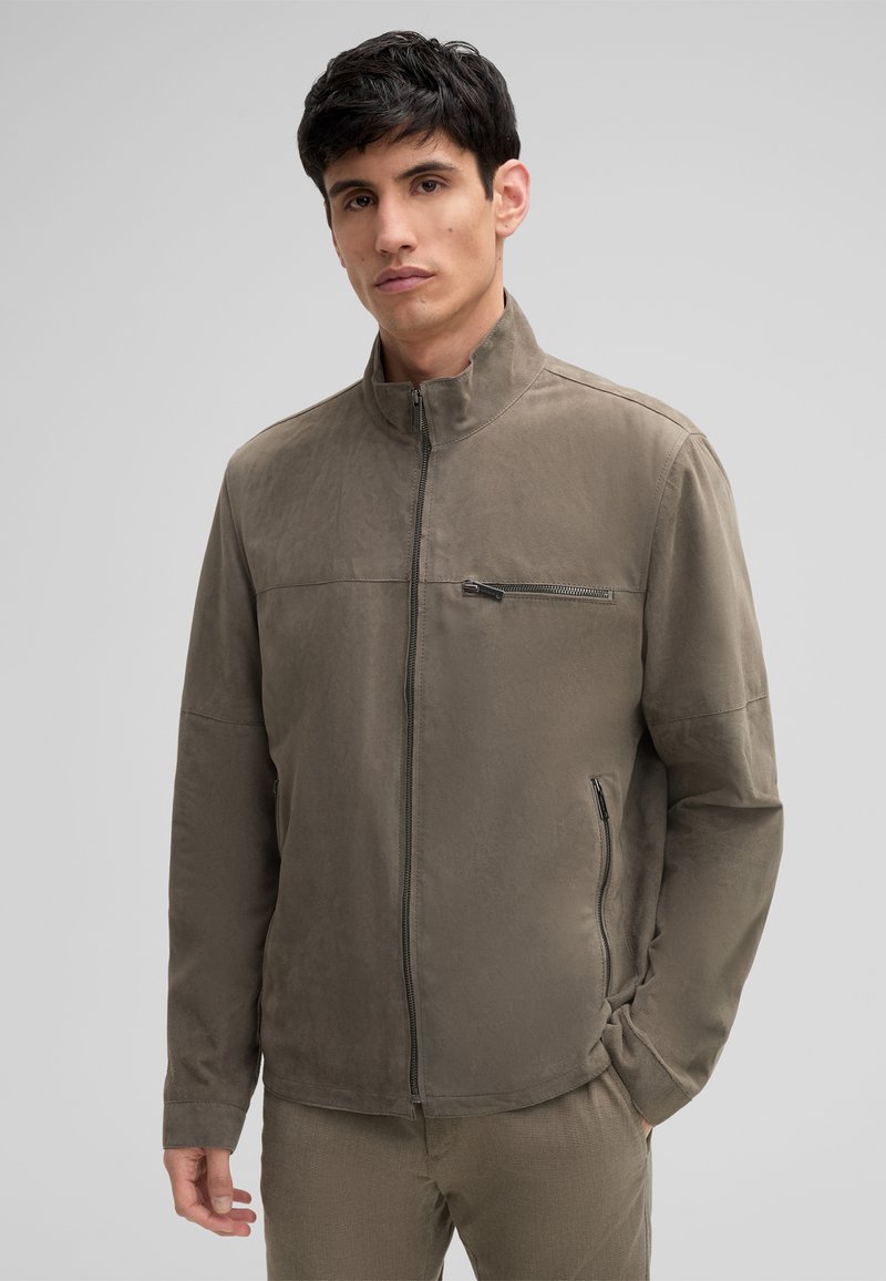 Bruine zip-up jas met een verhoogde kraag, gemaakt van een glad materiaal. Beschikt over een diagonale borstzak en zijzakken, minimalistisch ontwerp.