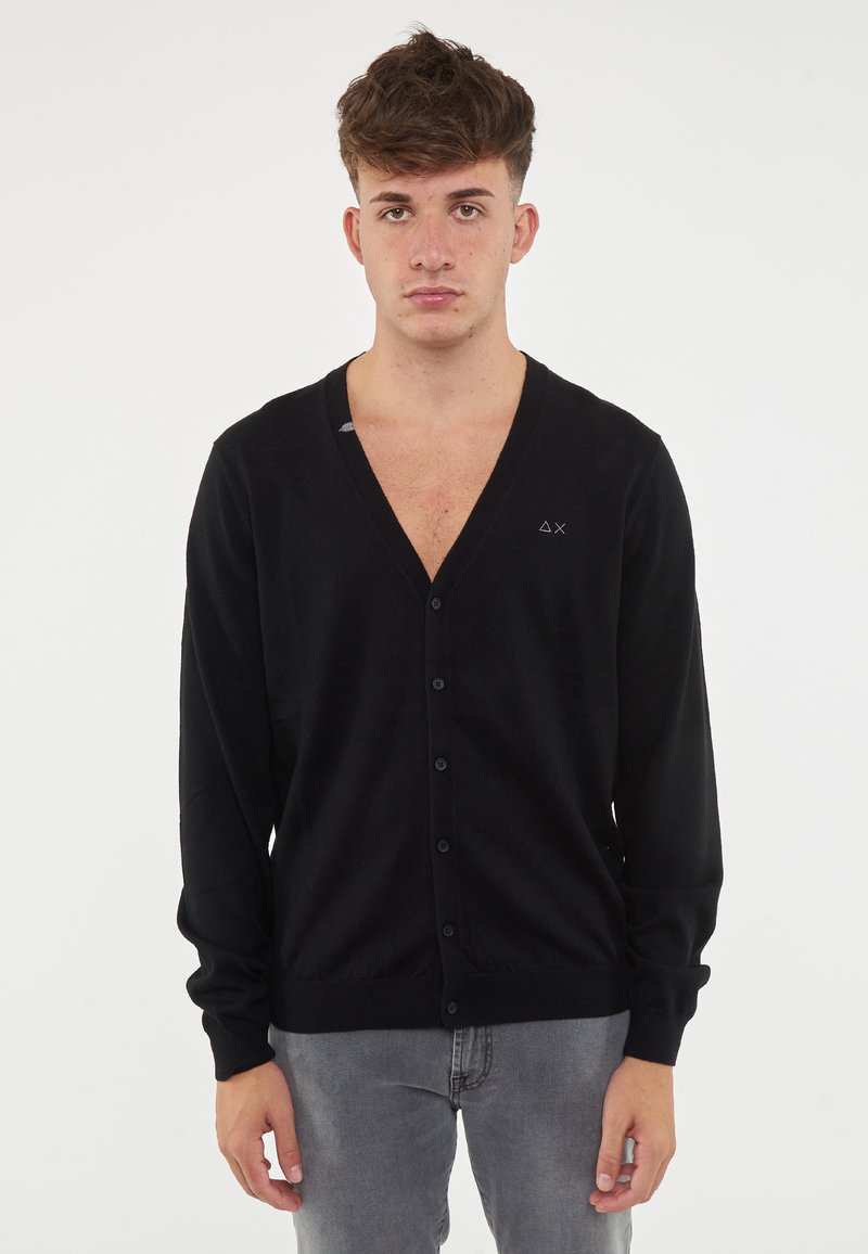 Cardigan nero con scollo a V e chiusura con bottoni. Maniche lunghe, texture morbida e un piccolo logo sul petto.