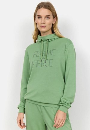 Grüner Sweatshirt mit hohem Kragen, verstellbaren Kordeln und dem Text "FEMME" und "FIERCE" in Dunkelgrau. Weiches Material und lockere Passform.