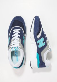 Laikku siniset ja harmaat lenkkitossut turkooseilla yksityiskohdilla, joissa on verkkokudosta ja mokkaa yläosa, valkoiset nauhat ja paksu valkoinen välipohja.