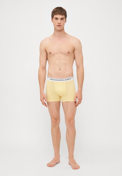 Žluté boxerky z elastického materiálu, s bílým pasem a logem 'POLO RALPH LAUREN'. Jednoduchý, přiléhavý design.