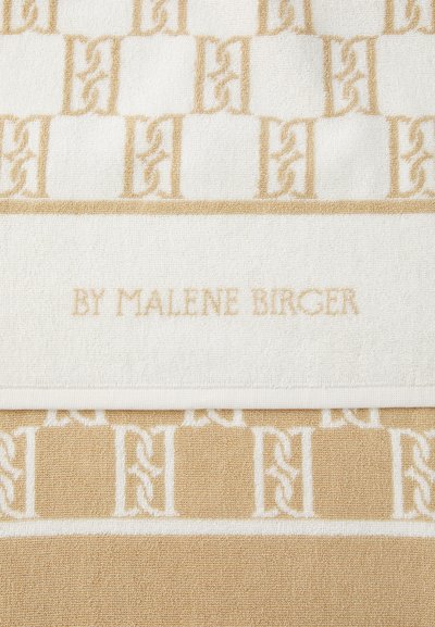 Pyyhe, jossa on geometrinen kuvio kermanvärisenä ja vaaleanbeigeinä, tekstuurilla varustetusta kankaasta. "BY MALENE BIRGER" on kohokuvioitu valkoiselle nauhalle.