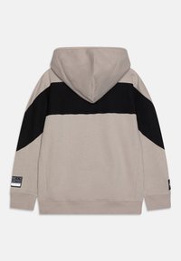 Sudadera con capucha en gris claro con una franja diagonal negra. Presenta un tejido texturizado y puños acanalados, con un detalle de etiqueta lateral.