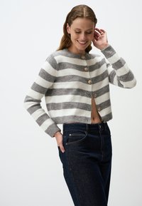 Gestreifter Cardigan in Hellgrau und Weiß, mit Rundhalsausschnitt, Knöpfen vorne und gerippten Bündchen. Trägt man über dunklen Jeans.