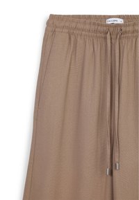Pantaloni beige a vestibilità rilassata con vita elastica, chiusura con cordino e tasche laterali. Tessuto liscio con una finitura leggermente testurizzata.