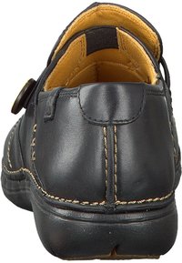 Schwarze Lederschuhe mit einer abgerundeten Rückseite, gelber Innenausstattung, sichtbaren Nähten und einem Knopfverschlussdetail an der Seite. Strukturiert Oberfläche.