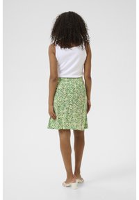 Blomstret nederdel i grønne nuancer med en sval design, lavet af letvægtsstof. Lukkes med lynlås i siden; parret med en hvid tanktop.