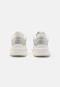 Baskets blanches avec des embellissements argentés, surfaces texturées au niveau du talon, et une languette de traction. Semelles épaisses avec un design rainuré pour une meilleure adhérence.
