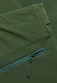 Groene stof met een gladde textuur, voorzien van een ritsvak met een bijpassende ritsenhouder en stiksels in een iets contrasterende kleur.