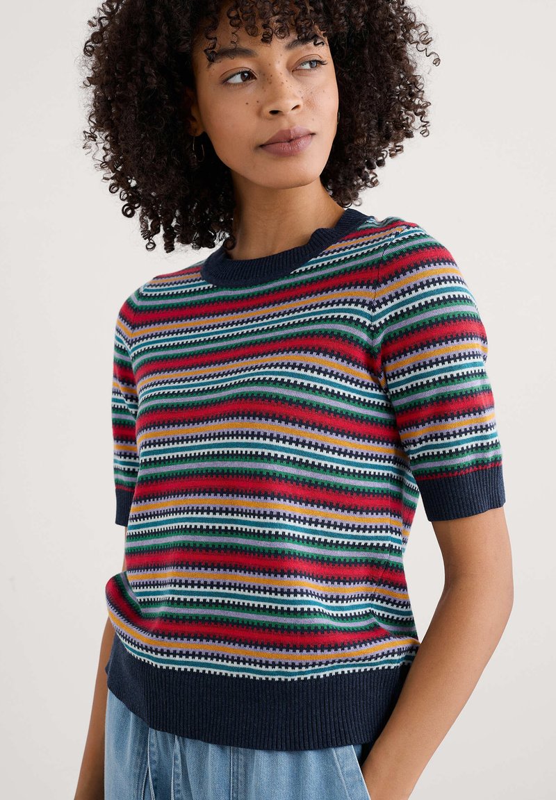 Suéter de punto con rayas horizontales en rojo, verde, azul marino y blanco. Mangas cortas con borde acanalado, cuello redondo y corte relajado.