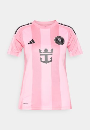 Rožinės spalvos dryžuotas futbolo marškinėlis su juodais akcentais, apvalios apykaklės, trumpomis rankovėmis ir logotipu krūtinės vietoje. Pagamintas iš orui pralaidaus audinio.