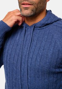 Navy Farbstellung, Kabelstrick-Hoodie aus weicher Wolle, mit einer Fronttasche und verstellbaren Kordeln am Kragen. Glatte Textur und taillierte Passform.