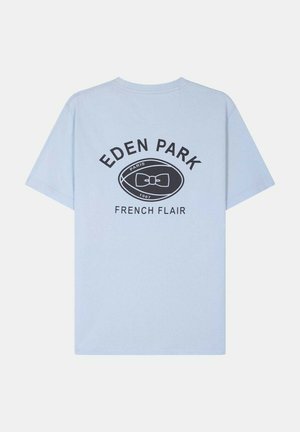T-shirt bleu clair à manches courtes avec le texte "EDEN PARK", un logo ovale présentant un nœud papillon, et "FRENCH FLAIR" imprimé dans le dos.