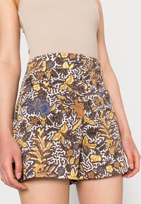 Korte broek met bloemenpatroon in wit, geel, bruin en blauw, met een hoge taille en zilveren knoopsluiting, gemaakt van lichtgewicht stof.