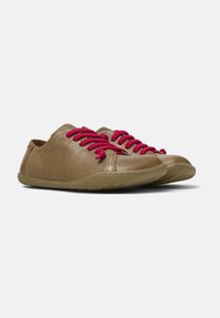 Scarpe di pelle marrone con lacci rosa, profilo basso, punta rotonda e suola in gomma flessibile. Presentano dettagli cuciti e un design casual.