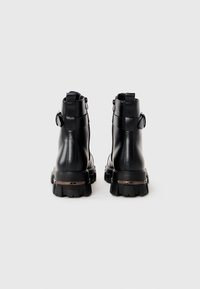 Black ankle boots made of smooth leather, featuring a chunky sole, rear pull tab, and zipper detail on the side for easy wear.