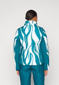 Tihendatud jope roheline-valge kombinatsioonis lainemustritega, kõrge krae ja tikitud tekstuuriga. Omab vormikohast lõiget ja kontrastseid varrukaid.